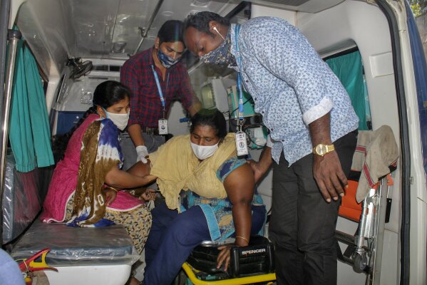 A patient is assisted by others to get down from an ambulance at the district government hospital in Eluru, Andhra Pradesh state, India, Tuesday, Dec.8, 2020. Health officials and experts are still baffled by a mysterious illness that has left over 500 people hospitalized and one person dead in this southern Indian state. (AP Photo)