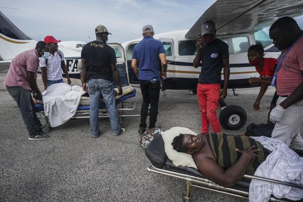 Residents injured by the 7.2 magnitude earthquake are taken on stretchers to a plane that will take them to the capital city of Port-au-Prince, from the airport in Les Cayes, Haiti, Thursday, Aug. 19, 2021. (AP Photo/Fernando Llano)
