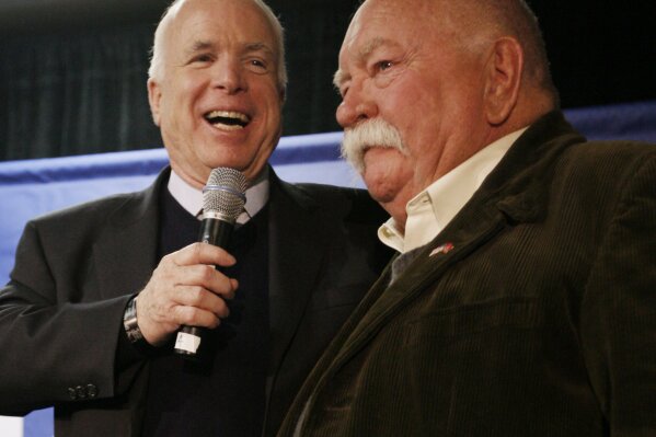 FILE - In this Jan. 4, 2008, file photo, Republican presidential hopeful, Sen. John McCain, R-Ariz., left, introduces actor, Wilford Brimley, after making a reference to fellow Republican presidential hopeful, former Arkansas Gov. Mike Huckabee, campaigning with actor Chuck Norris, as McCain makes a campaign stop at Hudson Veterans of Foreign Wars Post 5791, in Hudson, N.H. Brimley, who worked his way up from stunt performer to star of film such as “Cocoon” and “The Natural,” has died. He was 85. Brimley’s manager Lynda Bensky said the actor died Saturday morning, Aug. 1, 2020 in a Utah hospital. (AP Photo/Charles Dharapak, File)