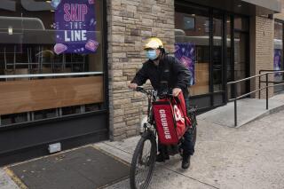 FILE - In this April 21, 2021 file photo, a delivery man bikes with a food bag from Grubhub in New York.  The three biggest food delivery companies, DoorDash, Grubhub and Uber Eats, are suing the City of New York, Friday, Sept. 10,  over its law to permanently limit the amount they can charge restaurants that use their services.(AP Photo/Mark Lennihan, File)