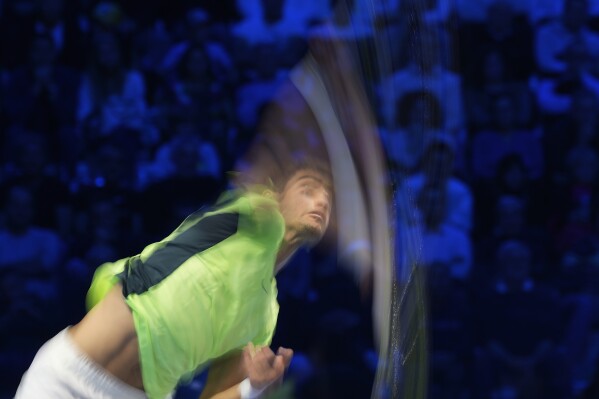In this image taken with a slow shutter speed, Spain's Carlos Alcaraz serves the ball to Germany's Alexander Zverev during their singles tennis match of the ATP World Tour Finals at the Pala Alpitour, in Turin, Italy, Monday, Nov. 13, 2023. (AP Photo/Antonio Calanni)