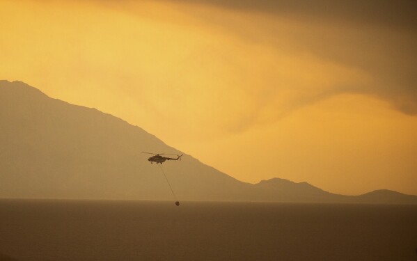 A helicopter releases water over the village of Dikela, near Alexandroupolis town, in the northeastern Evros region, Greece, Aug. 22, 2023. (AP Photo/Achilleas Chiras)