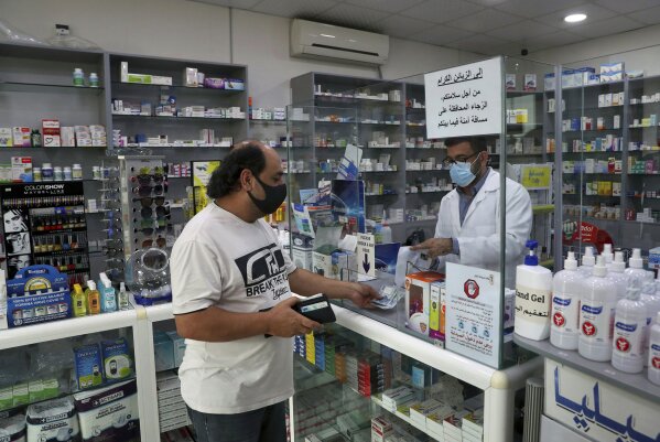 Pharmacist Ziad Jomaa sells medicine to a customer in his pharmacy in Bchamoun village outside of Beirut, Lebanon, Wednesday, Oct. 28, 2020. Drugs for everything from diabetes and blood pressure to anti-depressants and fever pills used to deal with COVID-19 have disappeared from shelves around Lebanon. Officials and pharmacists say the shortage was fueled by panic buying after the governor of the Central Bank suggested he will cut subsidies on medicines. (AP Photo/Bilal Hussein)