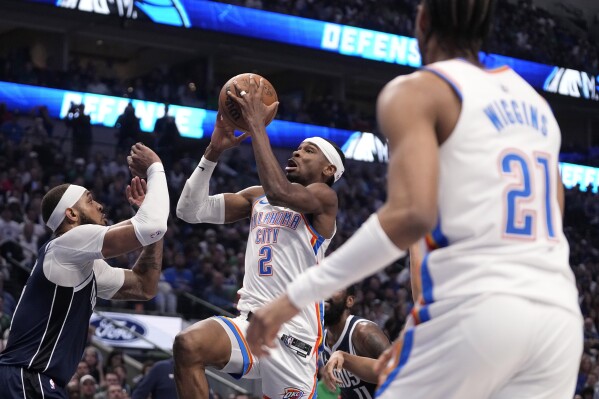 Oklahoma City Thunder guard Shai Gilgeous-Alexander (2) leaps to the basket to shoot as Dallas Mavericks' Daniel Gafford, left, defends in the first half in Game 4 of an NBA basketball second-round playoff series Monday, May 13, 2024, in Dallas. (AP Photo/Tony Gutierrez)