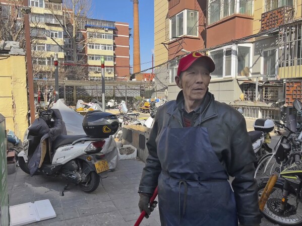 Duan Shuangzhu, 68, a waste collector who moved to Beijing in late 1990s from a small village in central China's Shanxi, stands next to a rubbish bin while working in Beijing on March 1, 2024. China’s first generation of migrant workers played an integral role in the country's transformation from an impoverished nation to an economic powerhouse. Now, they're finding it hard to find work, both because they're older and the economy is slowing. (AP Photo)
