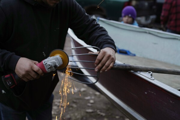 Donovan Martin sharpens a spear before heading out to spearfish on Round Lake Saturday, April 13, 2024, near Hayward, Wis. (AP Photo/John Locher)