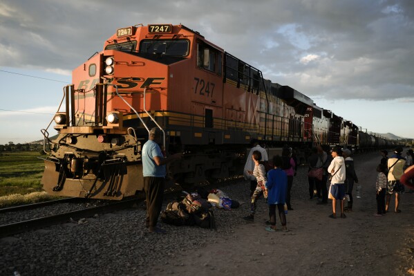 Migrants watch a train go past as they wait along the train tracks hoping to board a freight train heading north, one that stops long enough so they can hop on, in Huehuetoca, Mexico, Sept. 19, 2023. Ferromex, Mexico's largest railroad company announced that it was suspending operations of its cargo trains due to the massive number of migrants that are illegally hitching a ride on its trains moving north towards the U.S. border. (AP Photo/Eduardo Verdugo)