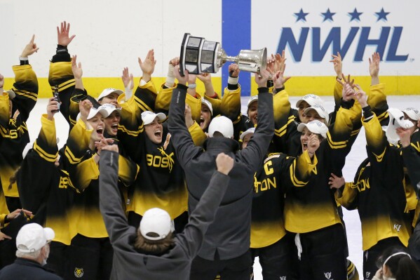 FILE - Boston Pride players cheer as coach Paul Mara hoists the NWHL Isobel Cup trophy after the team's win over the Minnesota Whitecaps in the championship hockey game in Boston, Saturday, March 27, 2021. Organizers announced plans Friday, June 30, 2023, to launch a new women’s professional hockey league in January that they hope will provide a stable, economically sustainable home for the sport's top players for years to come. The agreement ends a long standoff between the seven-team Professional Hockey Federation (PHF) and the PWHPA. (AP Photo/Mary Schwalm, File)
