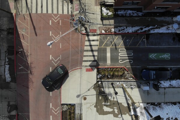 A car takes a corner at the intersection of Adams and 12th in Hoboken, N.J., Thursday, Feb. 22, 2024. This intersection has a number of pedestrian safety features, including planters as curb extenders, high visibility markings and textured surfaces, all in an effort to increase pedestrian safety. (AP Photo/Seth Wenig)