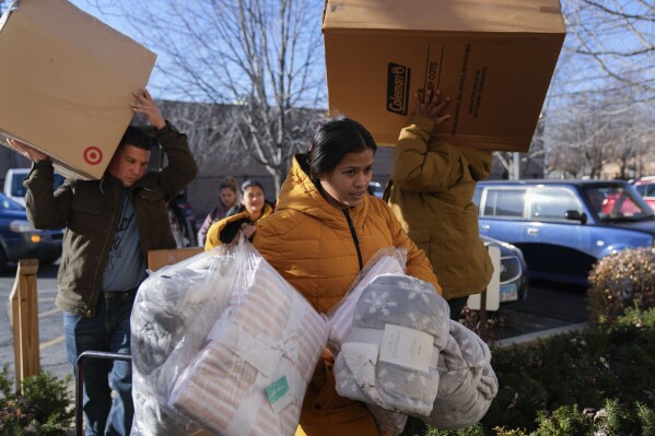 Carolina Gonzalez of Venezuala carries supplies into the Chicago City Life Center Wednesday, Nov. 29, 2023, in Chicago. The community center and church welcomed about 40 migrants who were previously living at police stations and airports. (AP Photo/Erin Hooley)