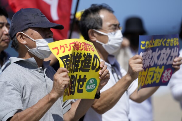 La gente protesta en una playa hacia la planta de energía nuclear de Fukushima Daiichi, dañada por un enorme terremoto y tsunami el 11 de marzo de 2011, en la ciudad de Namie, noreste de Japón, el jueves 24 de agosto de 2023. El operador de la Fukushima Daiichi destrozada por el tsunami Una planta de energía nuclear dice que comenzó a liberar su primer lote de agua radiactiva tratada en el Océano Pacífico el jueves, un paso controvertido, pero un hito en la batalla de Japón contra las crecientes reservas de agua radiactiva. (Foto AP/Eugene Hoshiko)