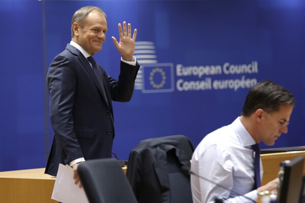 Poland's Prime Minister Donald Tusk, left, waves as he arrives for a round table meeting at an EU summit in Brussels, Friday, Dec. 15, 2023. European Union leaders conclude a second day of meetings in which they will discuss the situation in Gaza. (AP Photo/Omar Havana)
