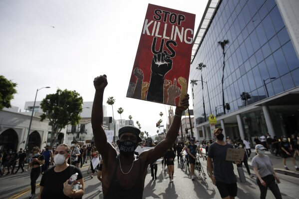 FILE - In this June 1, 2020, file photo, a protester carries a sign in the Hollywood area of Los Angeles during demonstrations over the death of George Floyd. Black people are facing a combination of stressors hitting simultaneously: isolation during the pandemic, a shortage of mental health care providers and racial trauma inflicted by repeated police killings of Black people. Black people suffer disproportionately from COVID-19 and have seen soaring rates in youth suicide attempts. (AP Photo/Marcio Jose Sanchez, File)