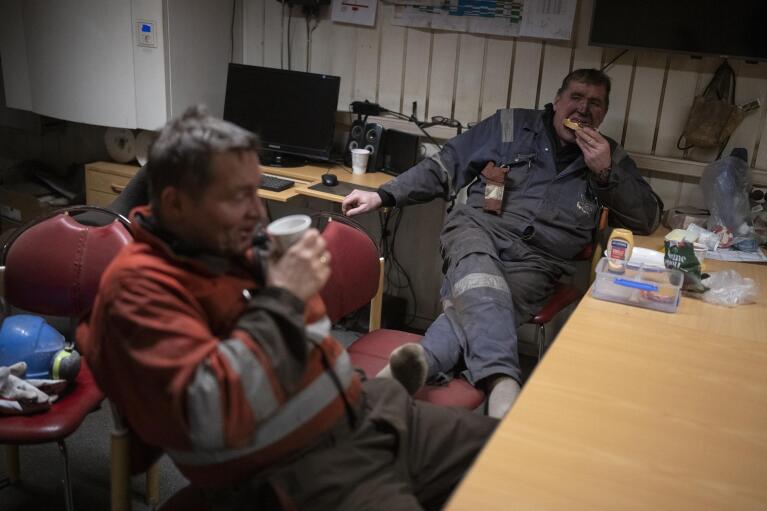 Coal miners rest during a shift in the break room of the Gruve 7 coal mine in Adventdalen, Norway, Monday, Jan. 9, 2023. The mine is scheduled to be shut down in two years, cutting carbon dioxide emissions in this fragile, rapidly changing environment, but also erasing the identity of a century-old mining community that fills many with deep pride even as the primary activities shift to science and tourism. (AP Photo/Daniel Cole)