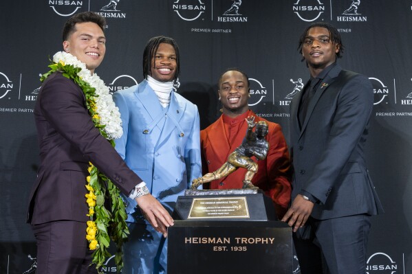 Heisman Trophy finalists, from left, Oregon's Dillon Gabriel, Colorado's Travis Hunter, Boise State's Ashton Jeanty and Miami's Cam Ward pose with the trophy during a college football press conference, Saturday, Dec. 14, 2024, in New York. (AP Photo/Corey Sipkin)