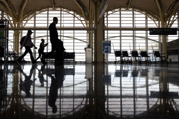 Travelers walk along a concourse at Reagan National Airport on July 19, 2024, in Arlington, Va. (AP Photo/Mark Schiefelbein, file)