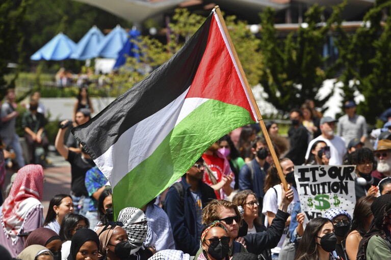 A pro-Palestinian protester holds a Palestinian flag while in front of Sproul Hall during a planned protest on the campus of UC Berkeley in Berkeley, Calif., on Monday, April 22, 2024. Hundreds of pro-Palestinian protesters staged a demonstration in front of Sproul Hall where they set up a tent encampment and are demanding a permanent cease-fire in the war between Israel and Gaza. (Jose Carlos Fajardo/Bay Area News Group via AP)