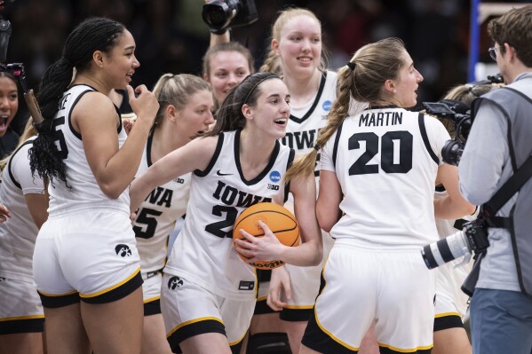 FILE - Iowa players, including guard Caitlin Clark, front center, forward Hannah Stuelke, front left, and guard Kate Martin (20) celebrate after an Elite 8 basketball game of the NCAA Tournament against Louisville, Sunday, March 26, 2023, in Seattle. Iowa will attempt to set the all-time women's basketball attendance record when it hosts DePaul in an outdoor exhibition at 69,000-seat Kinnick Stadium on Oct. 15, the school announced Thursday, Aug. 10, 2023. (AP Photo/Caean Couto, File)