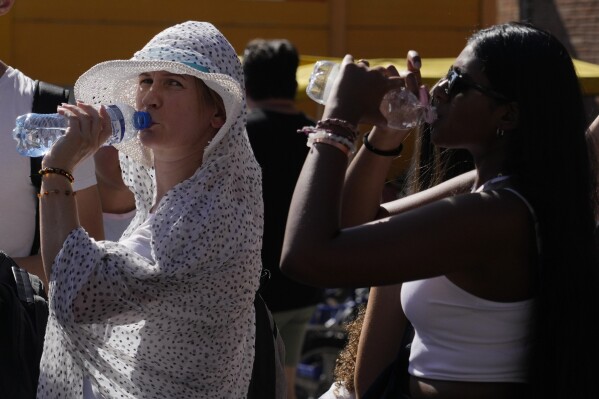 FILE - Tourists sip cold water as they shelter from a hot sunny afternoon near the Rome's Colosseum, July 5, 2023. A new study Tuesday, July 25, finds these intense and deadly hot spells gripping much of the globe in the American Southwest and Southern Europe could not have occurred without climate change. (AP Photo/Gregorio Borgia, File)