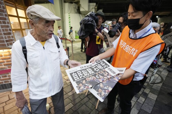 A pedestrian takes a copie of an extra edition of the Yomiuri newspaper reporting on Shigeru Ishiba becoming the winner of the Liberal Democratic Party's presidential election Friday, Sept. 27, 2024, in Tokyo. (AP Photo/Hiro Komae)