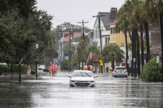 A car drives through a flooded street near the Battery, Sunday, Dec. 17, 2023, in Charleston, S.C. (Laura Bilson/The Post And Courier via AP)