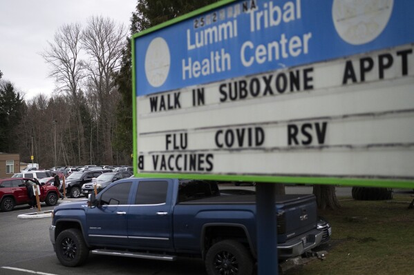 FILE - People walk through the parking lot of the Lummi Tribal Health Center advertising walk-in appointments for Suboxone, a medicine used to treat opioid dependence, on the Lummi Reservation, Thursday, Feb. 8, 2024, near Bellingham, Wash. A bill that would bring millions of dollars to tribes in Washington state to address the opioid crisis received unanimous support in the House, Friday, March 1, 2024. (AP Photo/Lindsey Wasson, File)