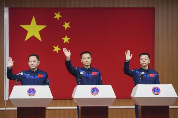 In this photo released by Xinhua News Agency, from left, Chinese astronauts for the upcoming Shenzhou-15 mission Zhang Lu, Fei Junlong and Deng Qingming wave during a meeting of the press at the Jiuquan Satellite Launch Center in northwest China on Monday, Nov. 28, 2022. Final preparations were being made Monday to send the new three-person crew to China's space station as it nears completion amid intensifying competition with the United States. (Liu Lei/Xinhua via AP)