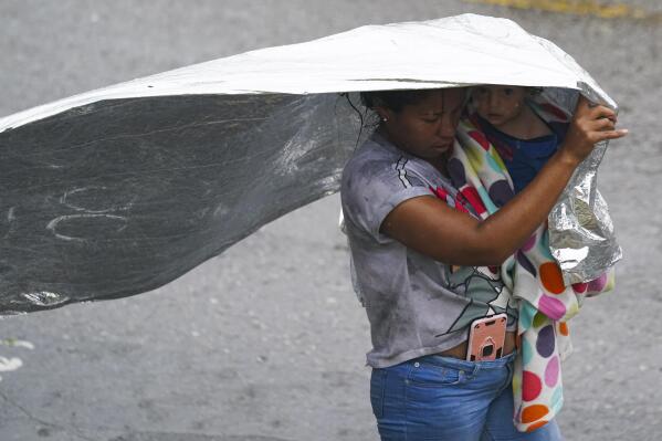 A Venezuelan migrant uses an emergency blanket as cover from the rain, near the banks of the Rio Grande in Matamoros, Mexico, Saturday, May 13, 2023. As the U.S. ended its pandemic-era immigration restrictions, migrants are adapting to new asylum rules and legal pathways meant to discourage illegal crossings. (AP Photo/Fernando Llano)