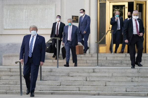 President Donald Trump, left, walks out of Walter Reed National Military Medical Center to return to the White House after receiving treatments for covid-19, Monday, Oct. 5, 2020, in Bethesda, Md. (AP Photo/Evan Vucci)