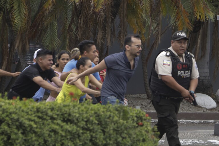 La policía evacua al personal de la estación del canal de televisión TC después de que un grupo de hombres armados irrumpiera en su set durante una transmisión en vivo, en Guayaquil, Ecuador, el martes 9 de enero de 2024. El país ha sido testigo de una serie de ataques después de que el gobierno impusiera una estado de emergencia tras la aparente fuga de prisión de un poderoso líder de una banda.  (Foto AP/César Muñoz)