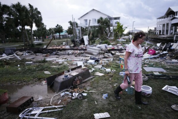 File - Jewell Baggett walks amidst debris strewn across the yard where her mother's home had stood, in Horseshoe Beach, Fla., after the passage of Hurricane Idalia, on Aug. 30, 2023. Information theft is on the rise. Frauds and scams often emerge during specific incidents such as the COVID pandemic, and in the wake of climate-related catastrophes. (AP Photo/Rebecca Blackwell, File)