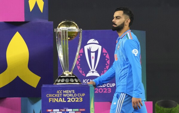India's Virat Kohli walks past ICC Men's Cricket World Cup trophy to receive player of the tournament award after the final match against Australia, in Ahmedabad, India, Sunday, Nov.19, 2023. (AP Photo/Aijaz Rahi)