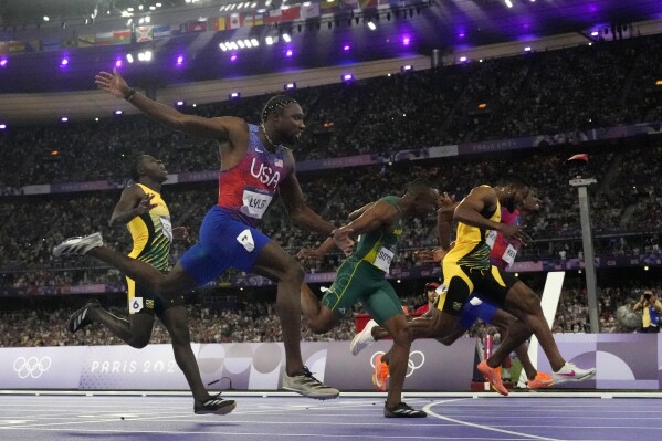 Noah Lyles, of the United States, second left, celebrates as he wins the men's 100-meter final ahead of Kishane Thompson, of Jamaica, at the 2024 Summer Olympics, Sunday, Aug. 4, 2024, in Saint-Denis, France. (AP Photo/David J. Phillip)
