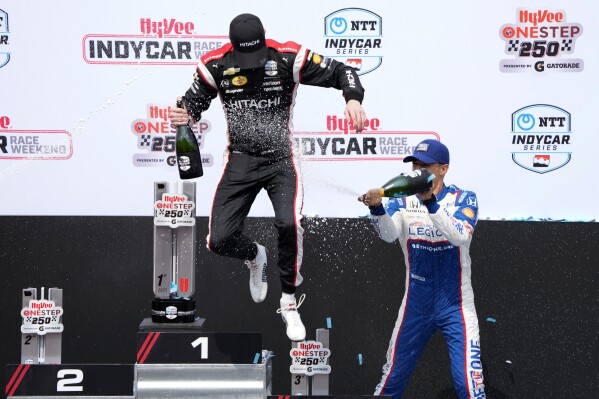 Josef Newgarden is sprayed with champagne by Alex Palou, of Spain, right, after winning an IndyCar Series auto race, Sunday, July 23, 2023, at Iowa Speedway in Newton, Iowa. (AP Photo/Charlie Neibergall)