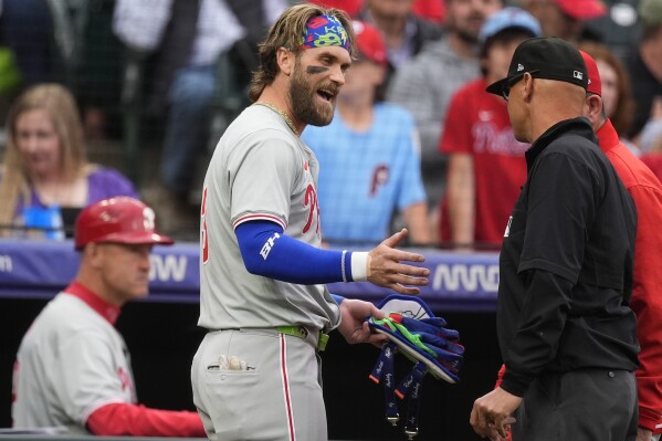 Philadelphia Phillies' Bryce Harper argues with second base umpire Vic Carpazza, right, as manager Rob Thomson, back right, listens after Harper was ejected for arguing after striking out to end the top of the first inning of the team's baseball game against the Colorado Rockies on Friday, May 24, 2024, in Denver. (AP Photo/David Zalubowski)