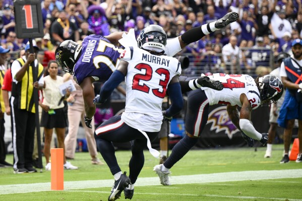 Baltimore Ravens' J.K. Dobbins gets past Houston Texans' Derek Stingley Jr. (24) and Eric Murray (23) for a touchdown during the first half of an NFL football game Sunday, Sept. 10, 2023, in Baltimore. (AP Photo/Nick Wass)
