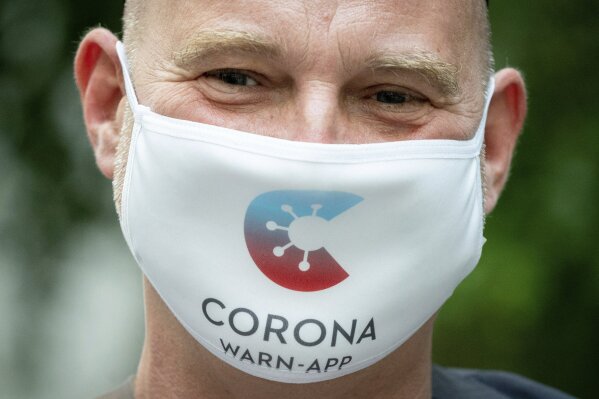 Rainer Knirsch, Telekom press spokesman, wears a mouth and nose protector with the app's logo at the beginning of a press conference on the 100-day Corona Warning App at the Federal Press Conference Center in Berlin, Germany, Wednesday, Sept. 23, 2020.(Kay Nietfeld/dpa via AP)
