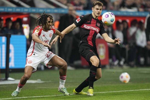 FILE - Bayern's Sacha Boey, left, and Leverkusen's Josip Stanisic challenge for the ball during the German Bundesliga soccer match between Bayer 04 Leverkusen and FC Bayern Munich at the BayArena in Leverkusen, Germany, on Feb. 10, 2024. Bayern Munich says fullback Sacha Boey is out with a hamstring tear after he recovered from a similar injury. Bayern says Boey tore muscle tissue in his left hamstring in training Wednesday, March 20, 2024. (AP Photo/Martin Meissner, File)