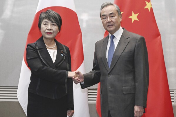 Japanese Foreign Minister Yoko Kamikawa, left, and her Chinese counterpart, Wang Yi, shake hands during their bilateral talk, in South Korea's southern port city of Busan, ahead of Sunday's three-way talks Saturday, Nov. 25, 2023. (Kyodo News via AP)