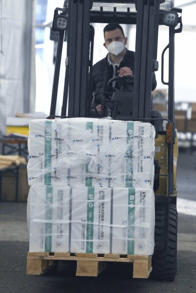 An employee unloads the newly arrived coronavirus vaccines from Chinese pharmaceutical company Sinopharm at the logistics base set up to in the parking lot of the government office in the 13th district of Budapest, Hungary, Monday, March 29, 2021. (Noemi Bruzak/MTI via AP)