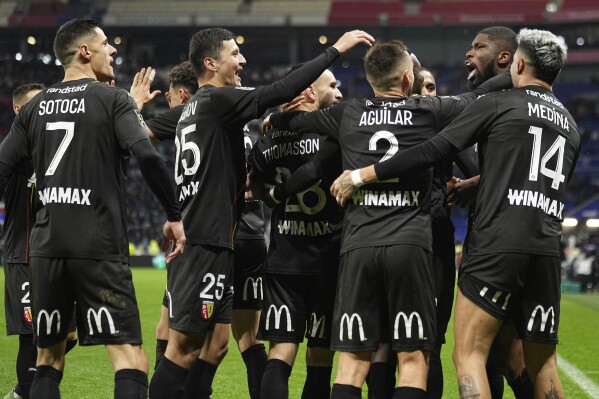 Lens' Kevin Danso celebrates with team mates after scoring his side's third goal during the French League One soccer match between Lyon and Lens at the Groupama stadium, outside Lyon, France, Sunday, March 3, 2024. (AP Photo/Laurent Cipriani)