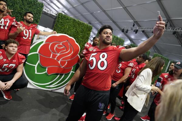 Utah defensive tackle Junior Tafuna (58) takes a selfie with teammates in from the of the logo during media day ahead of the Rose Bowl NCAA college football game Saturday, Dec. 31, 2022, in Pasadena, Calif. (AP Photo/Marcio Jose Sanchez)