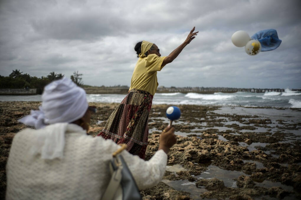 Gloria Esperanza Reyes makes her monthly offering of flowers and sugarcane syrup to Yemaya, the Yoruba goddess of the sea, in Havana, Cuba, Wednesday, Feb. 14, 2024. She also is venerated as Our Lady of Regla, a Black Madonna at a Catholic church across the Bay of Havana. (AP Photo/Ramon Espinosa)