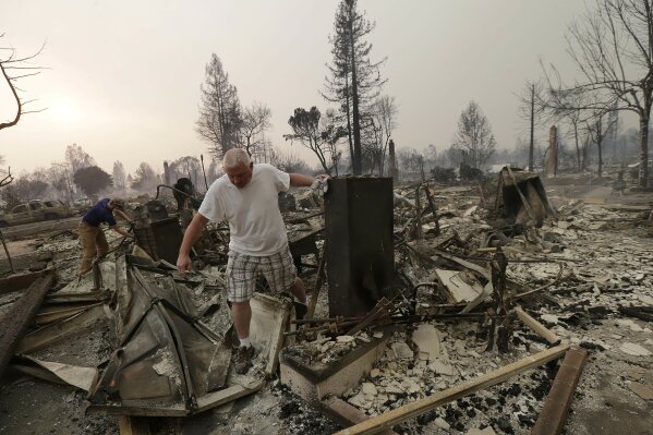 
              Mark Pedersen and his son Ben, left, look through the remains of their home destroyed by fires in Santa Rosa, Calif., Monday, Oct. 9, 2017. (AP Photo/Jeff Chiu)
            