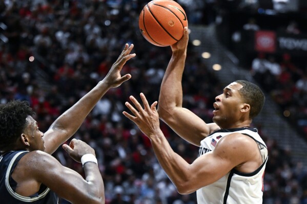 San Diego State forward Jaedon LeDee (13) shoots over Utah State forward Great Osobor (1) during the second half of an NCAA college basketball game Saturday, Feb. 3, 2024, in San Diego. (AP Photo/Denis Poroy)