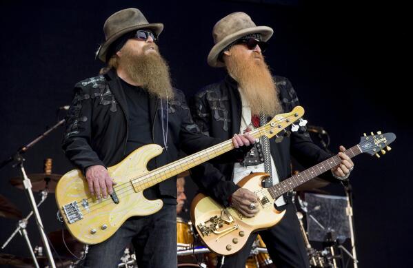 FILE - Dusty Hill, left, and Billy Gibbons from U.S rock band ZZ Top perform at the Glastonbury music festival in Somerset, England, June 24, 2016. ZZ Top has announced that Hill, one of the Texas blues trio's bearded figures and bassist, has died at his Houston home. He was 72. In a Facebook post, bandmates Billy Gibbons and Frank Beard revealed Wednesday, July 28, 2021, that Hill had died in his sleep. (Photo by Jonathan Short/Invision/AP, File)