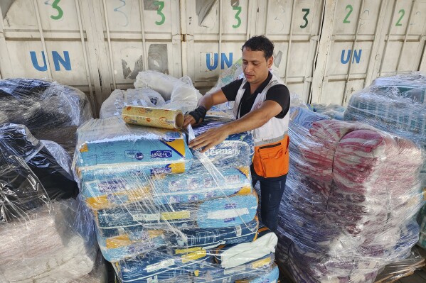 FILE - A United Nations worker prepares aid for distribution to Palestinians at UNRWA warehouse in Deir Al-Balah, Gaza Strip, on Monday, Oct. 23, 2023. The spokesperson for Israel's welfare ministry says it has stopped providing the documentation needed for international aid workers to renew their visas because the ministry does not have the investigative muscle to look into their potential militant affiliations. (AP Photo/Hassan Eslaiah, File)