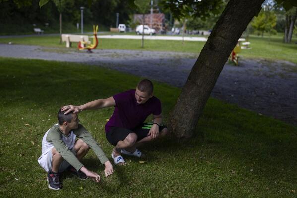 Timofey, right, touches Sasha's head in Loue, western France, Saturday, July 2, 2022. At 17, Timofey was suddenly the father to all his siblings when they were separated from their parents during the war. (AP Photo/Jeremias Gonzalez)