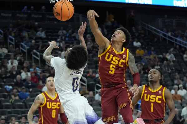 Southern California's Boogie Ellis (5) fouls Washington's Koren Johnson (0) during the second half of an NCAA college basketball game in the first round of the Pac-12 tournament Wednesday, March 13, 2024, in Las Vegas. (AP Photo/John Locher)