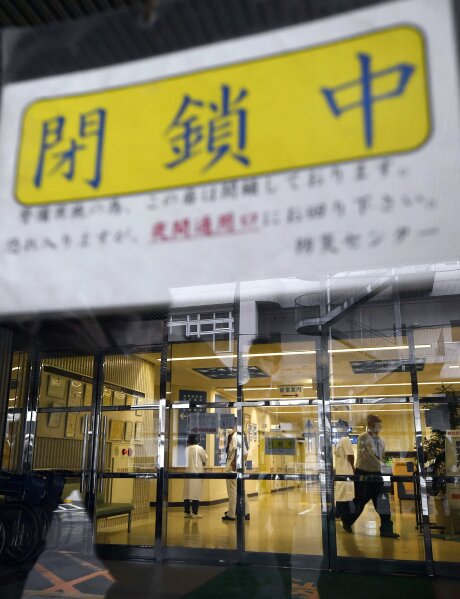 In this Feb. 16, 2020, photo, an entrance is blocked at Saiseikai Arida Hospital in Yuasa in the western Japanese prefecture of Wakayama, where a doctor was confirmed to have been infected with a new coronavirus. Hospitals in Japan are increasingly turning away sick people in ambulances as the country braces for a surge in coronavirus infections. The Japanese Association for Acute Medicine and the Japanese Society for Emergency Medicine say emergency medicine has already collapsed with many hospitals refusing to treat people including those suffering strokes, heart attacks and external injuries. The yellow sign at top reads: "Closed." (Kyodo News via AP)